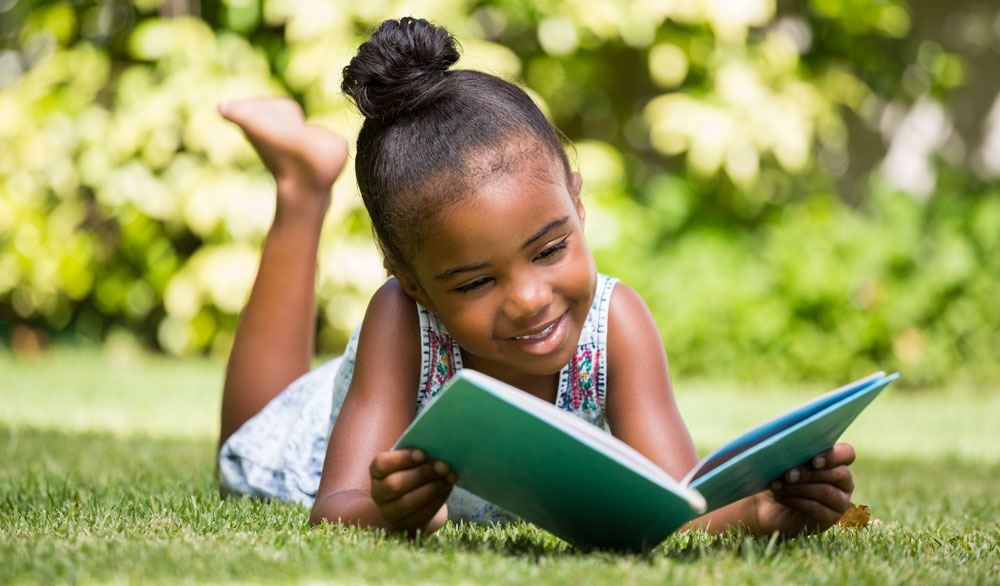 girl reading outside in grass