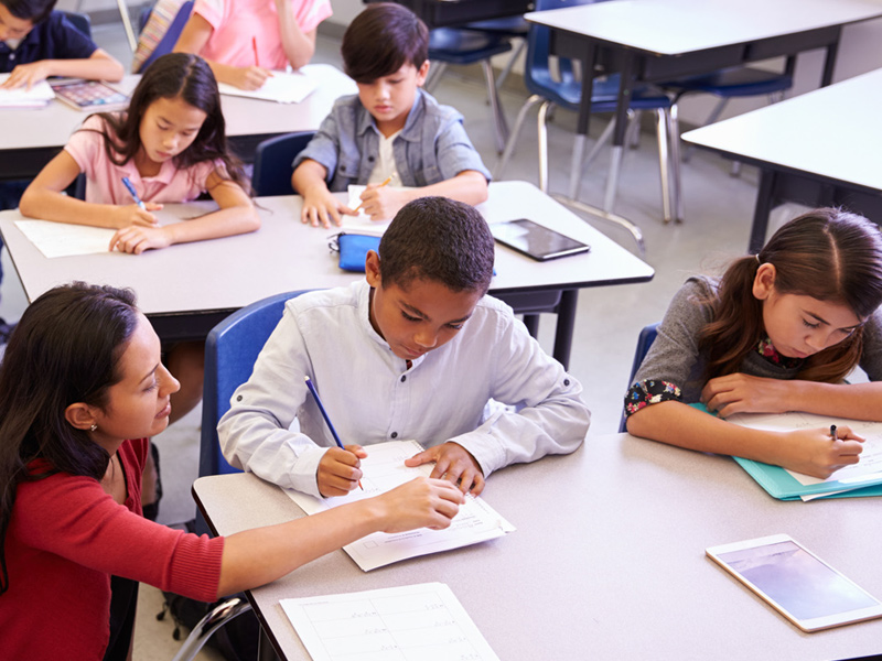 Teacher and student working on writing in classroom