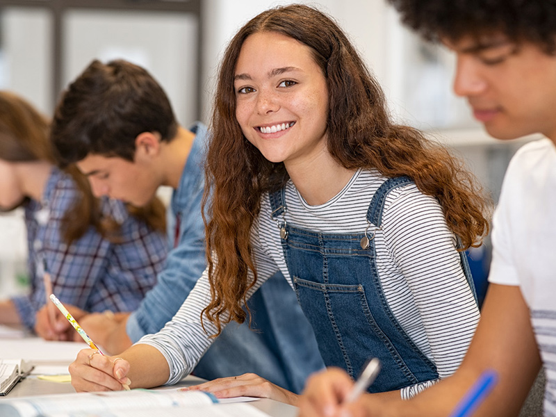 Girl student looking at camera while in writing class