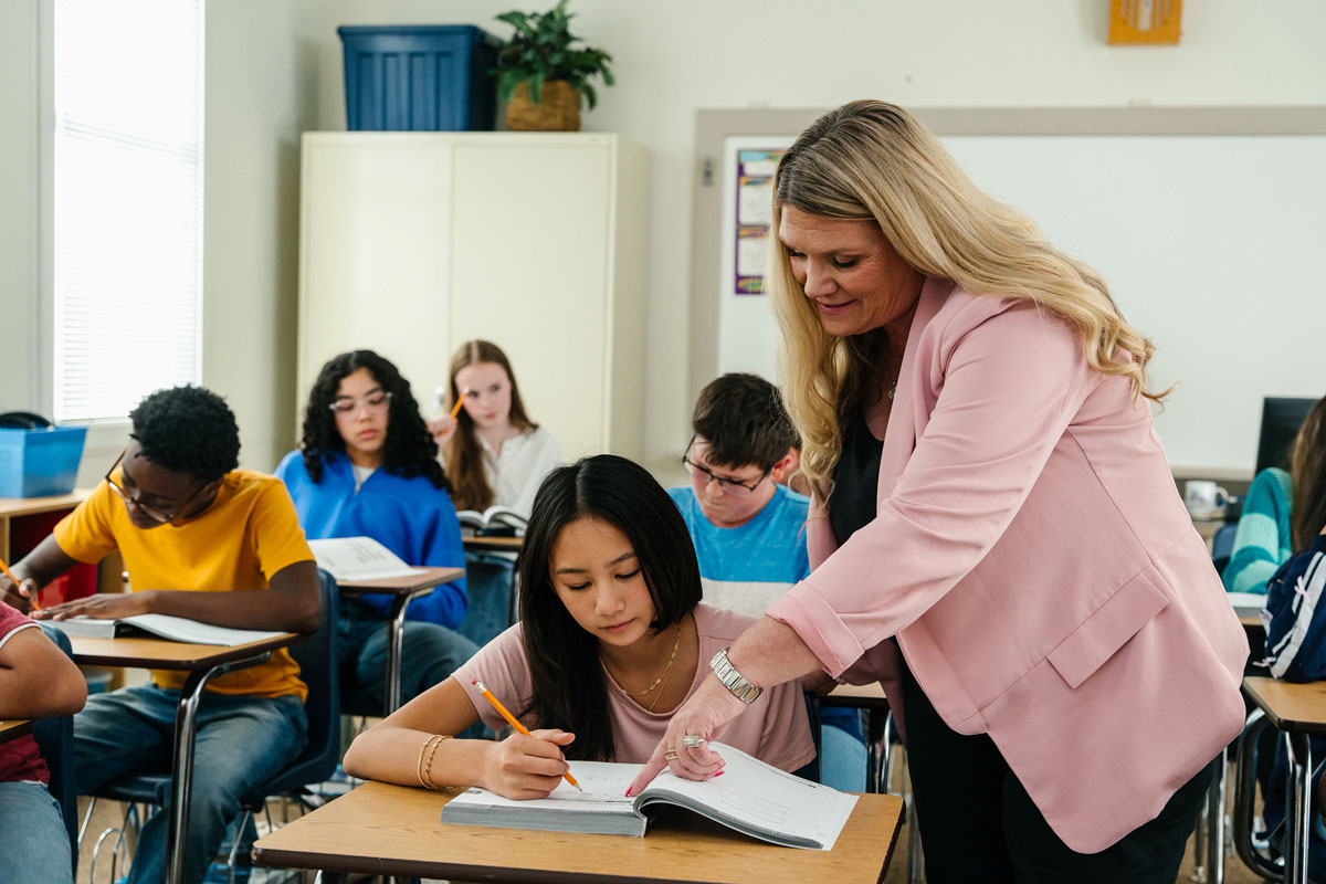 Teacher helping student at desk