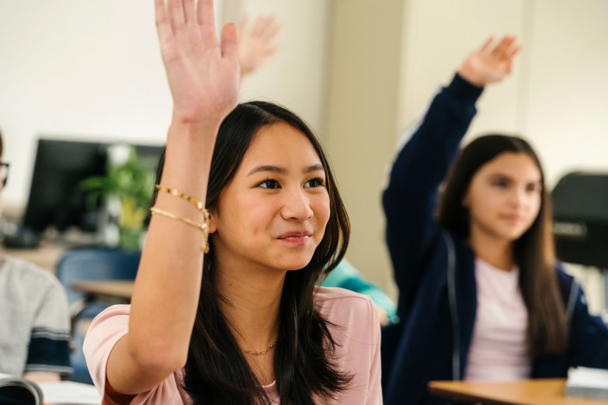 Students raising hands in classroom