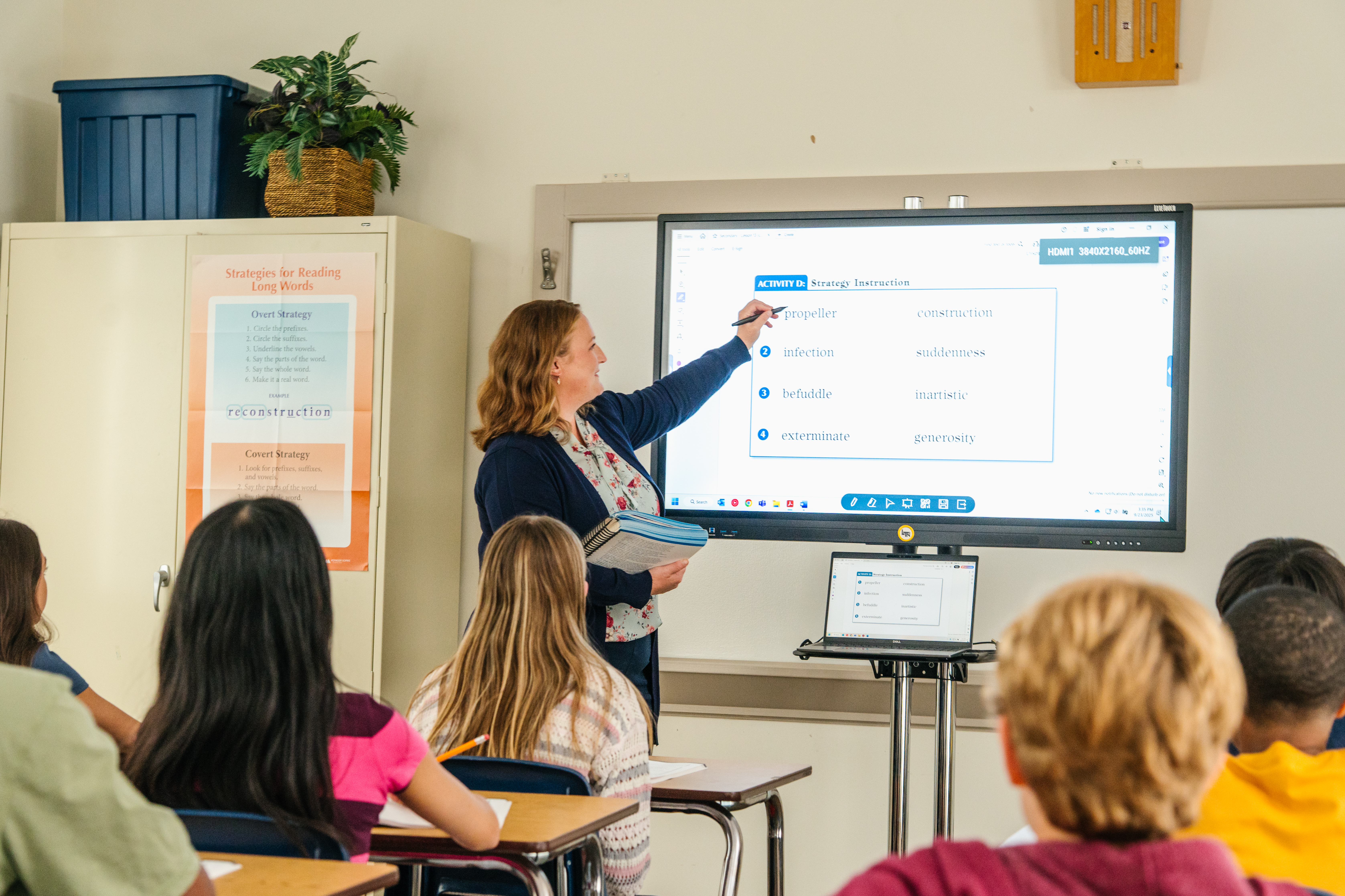 Teacher leading an explicit phonics lesson, such as using letter cards, a sound wall, or a whiteboard with phoneme-grapheme correspondences displayed