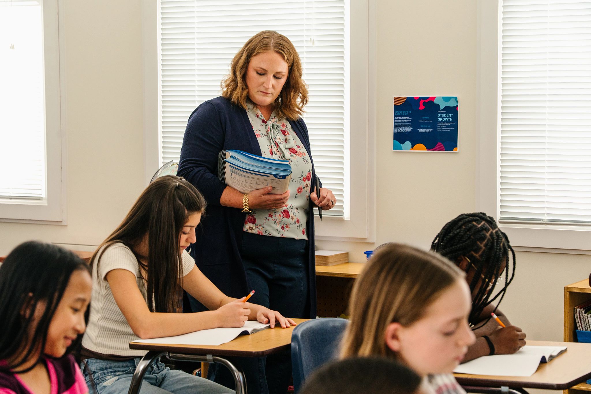 A teacher providing one-on-one feedback during a timed reading check, such as an educator with a clipboard or tablet tracking a student‘s oral reading in a classroom or hallway setting