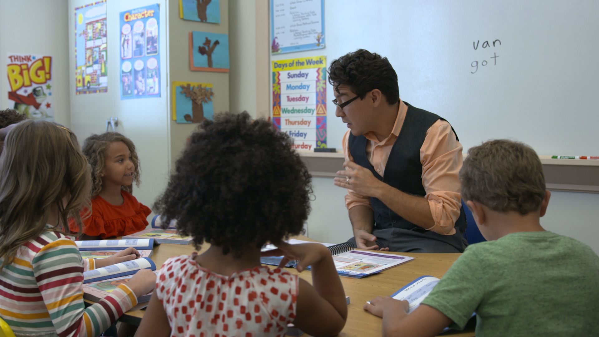 An educator reading aloud with students gathered together.