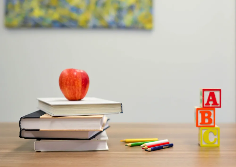 Apple set on top of stack of books on a table